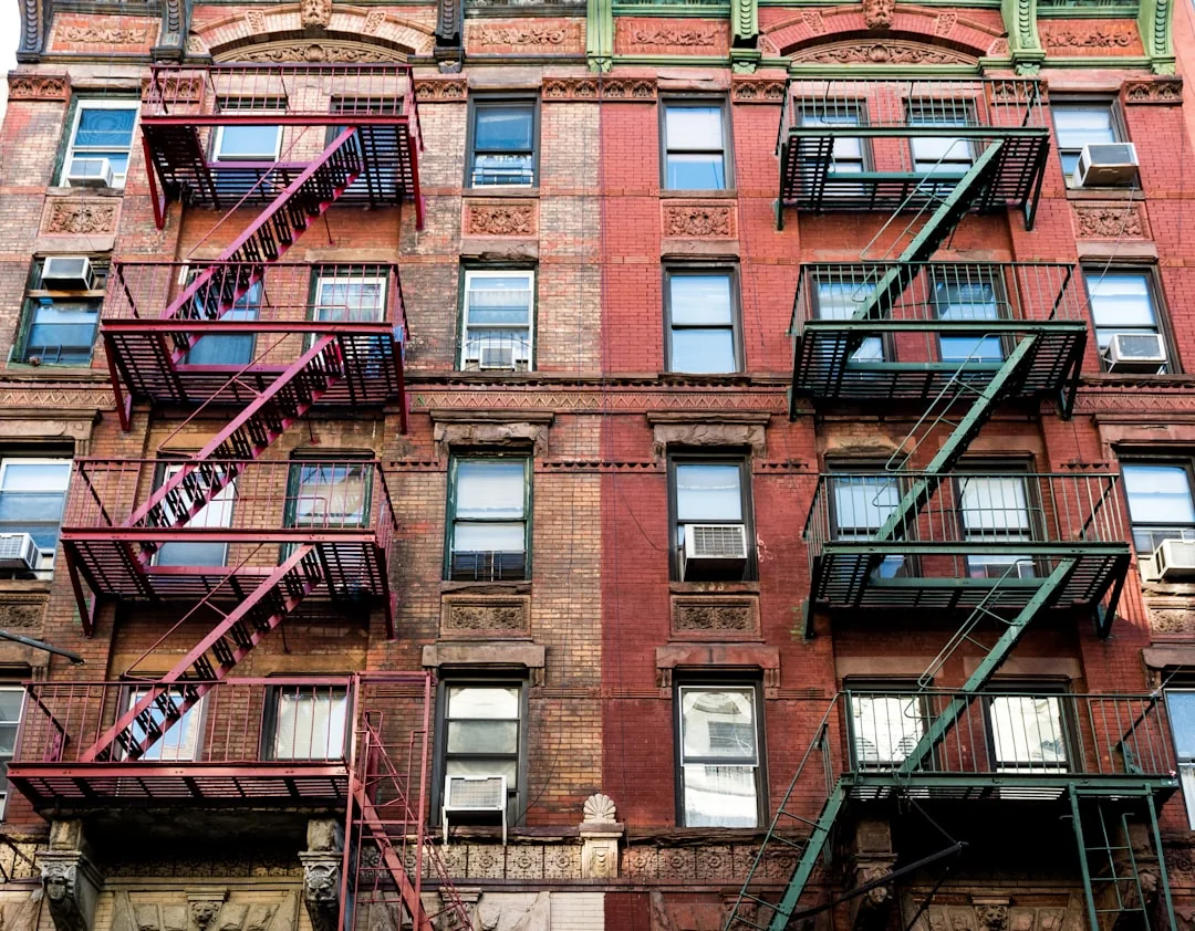 Trois laveurs de vitres suspendus à des cordes nettoient en journée la façade vitrée d’un immeuble moderne.
