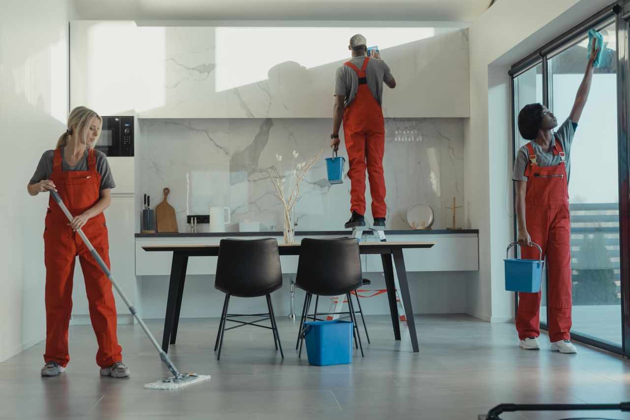 services-04 Group of cleaners in red uniforms mopping and wiping glass in a modern dining room.